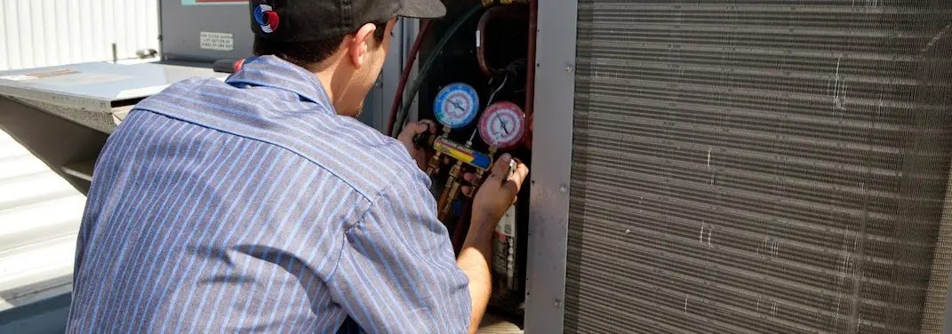 HVAC technician servicing a condenser unit in New Brunswick
