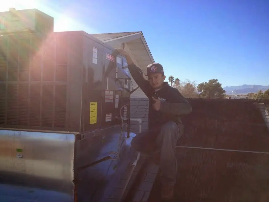 HVAC technician performing AC Tune-Up on a rooftop unit in New Brunswick
